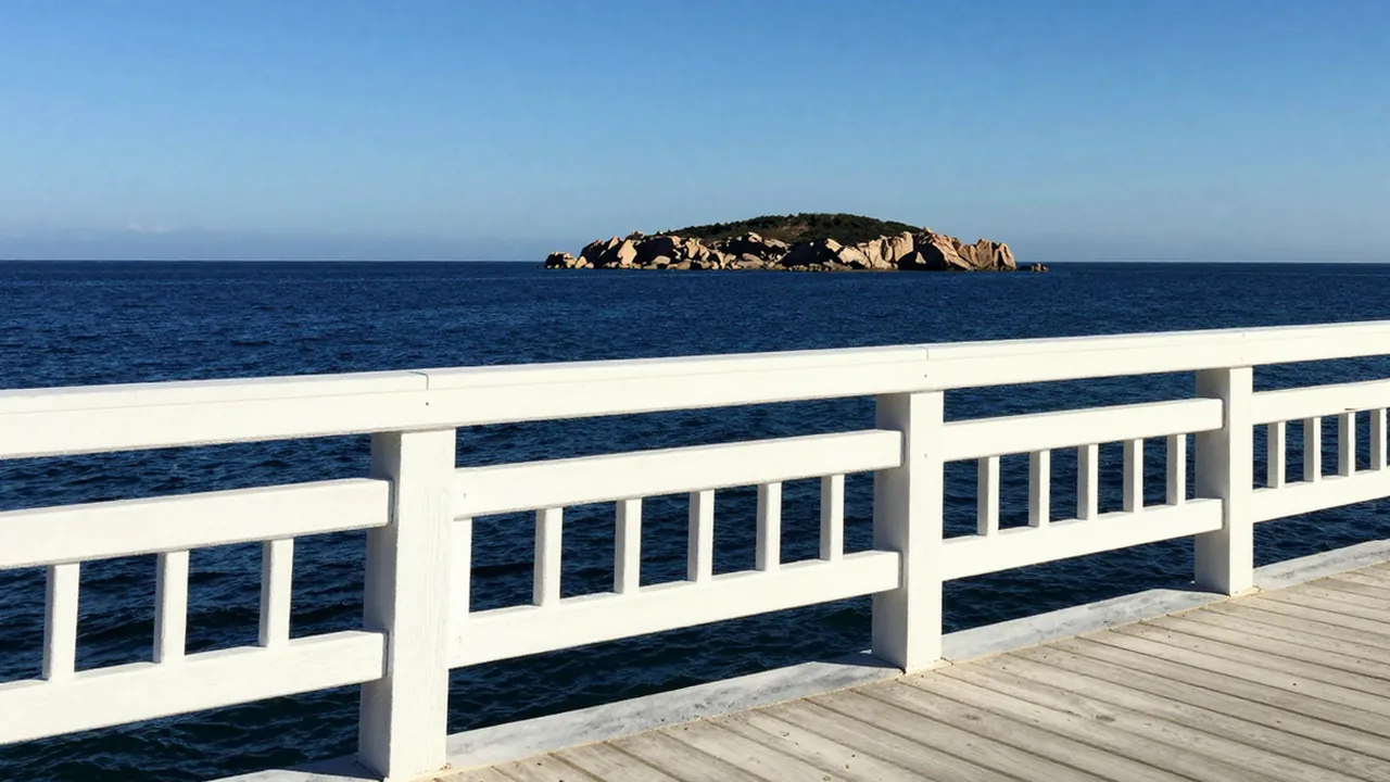 晴天的海邊木棧道，欄杆外是平靜的海面，遠處有一座小島
